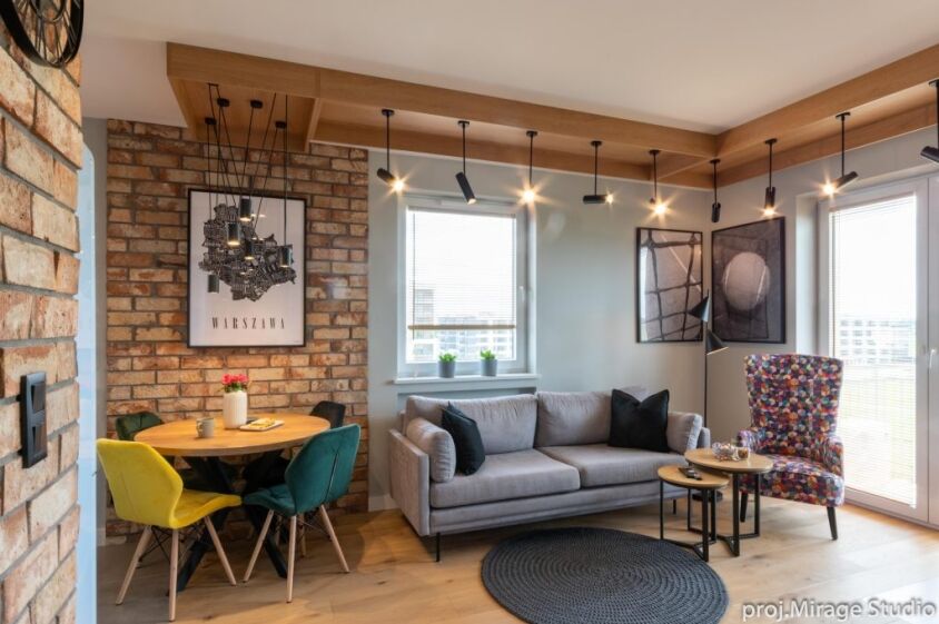 loftowy-klimat-mieszkanie-loft-warszawa-18 Mieszkanie w stylu loft i salon z ceglaną ścianą, jasną sofą i kolorowym fotelem.